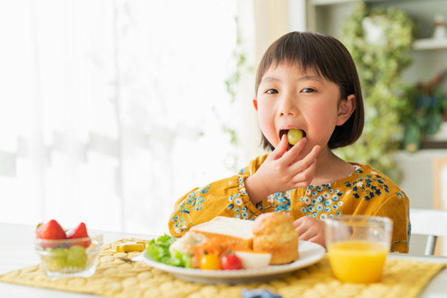 Una bambina giapponese che mangia frutta